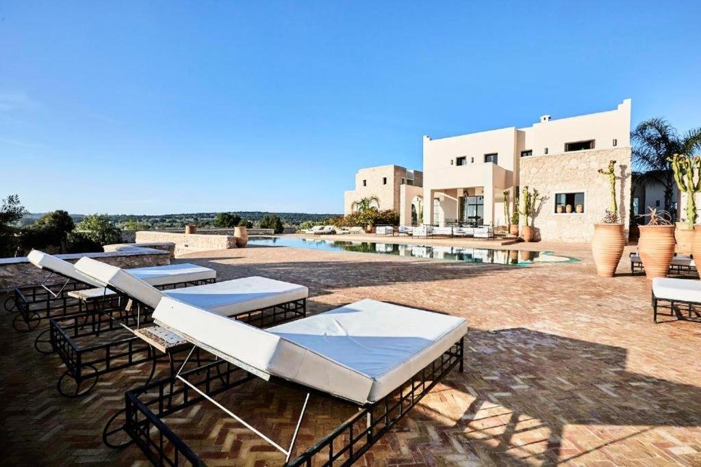 Piscine extérieure entourée de transats face à la villa
